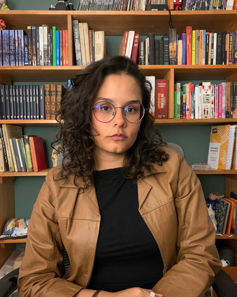 Bruna Bertuol, psicóloga clínica, em seu consultório em frente a uma estante de livros